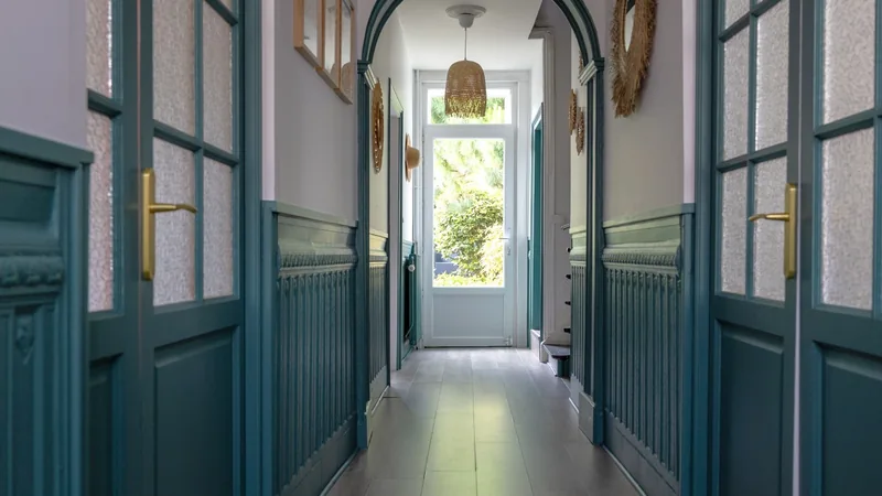 Couloir rénové du cabinet d'avocate à Marchiennes avec boiseries anciennes peintes en vert et portes vitrées.